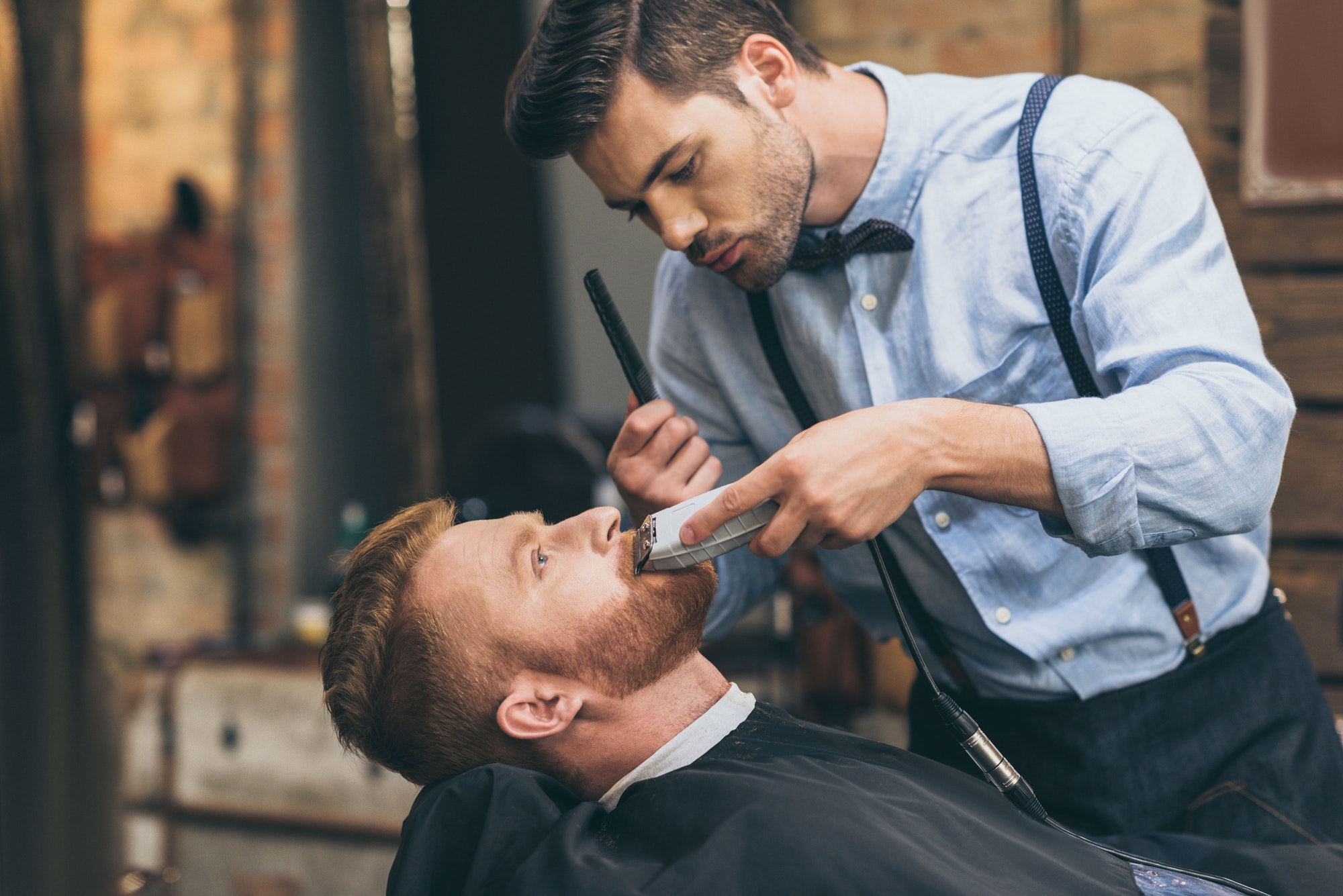 male-barber-trimming-customers-beard-in-barber-shop.jpg